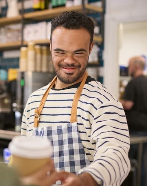 Black man with Down Syndrome working at a cafe serving coffee