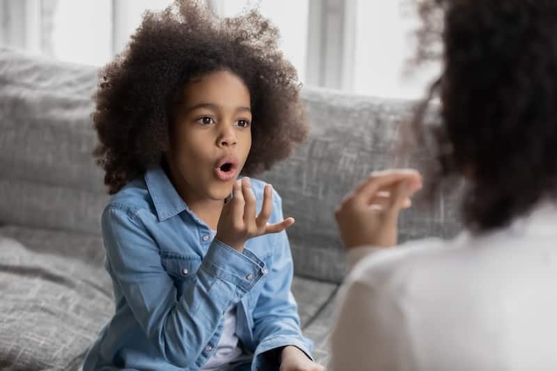 Black child learning sign language.