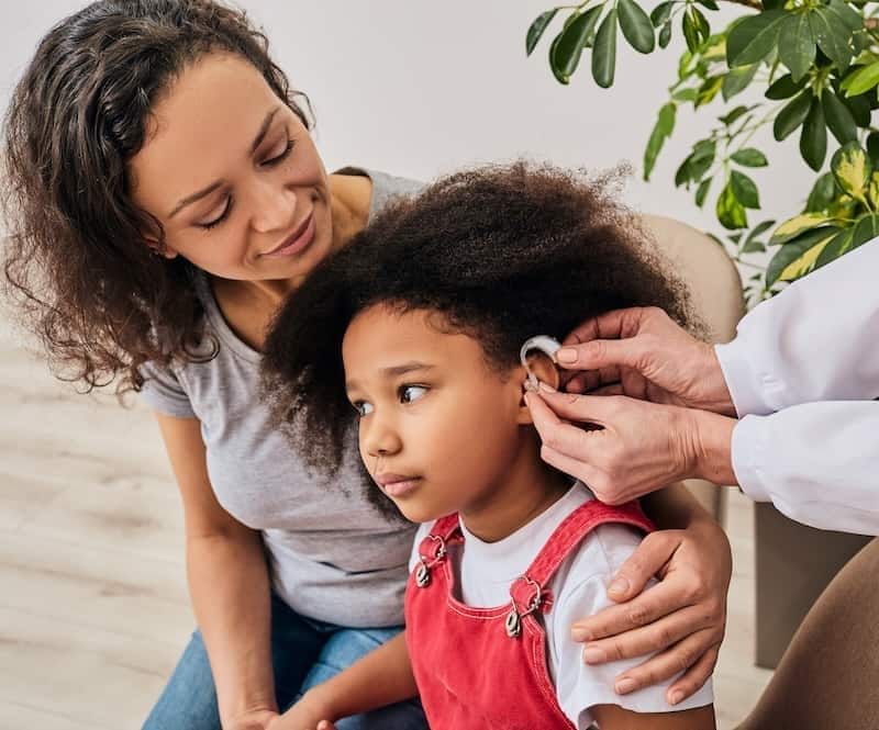 Black child getting hearing aid