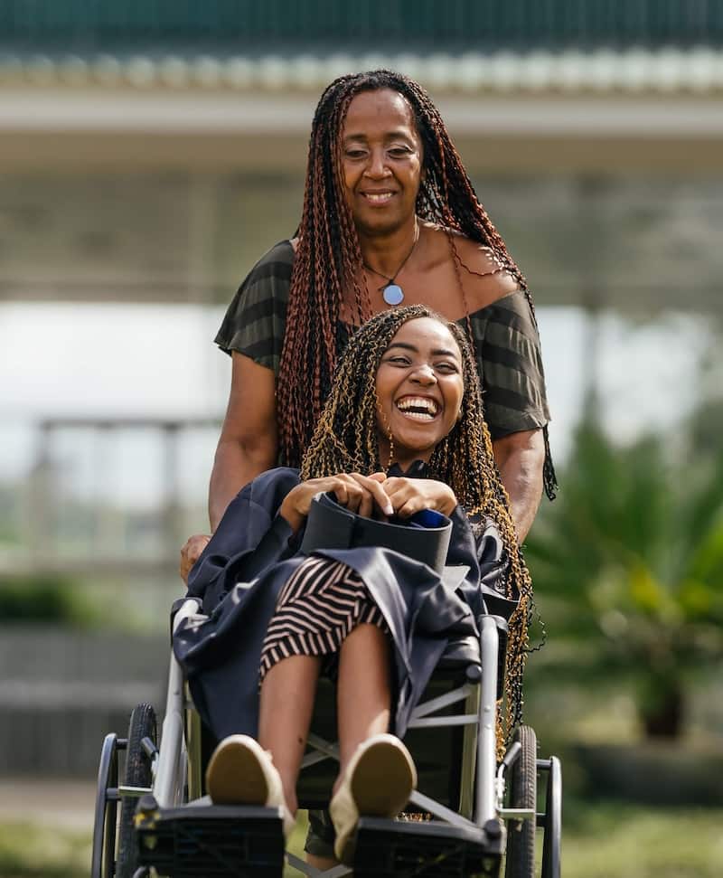 Happy black child being pushed in wheelchair